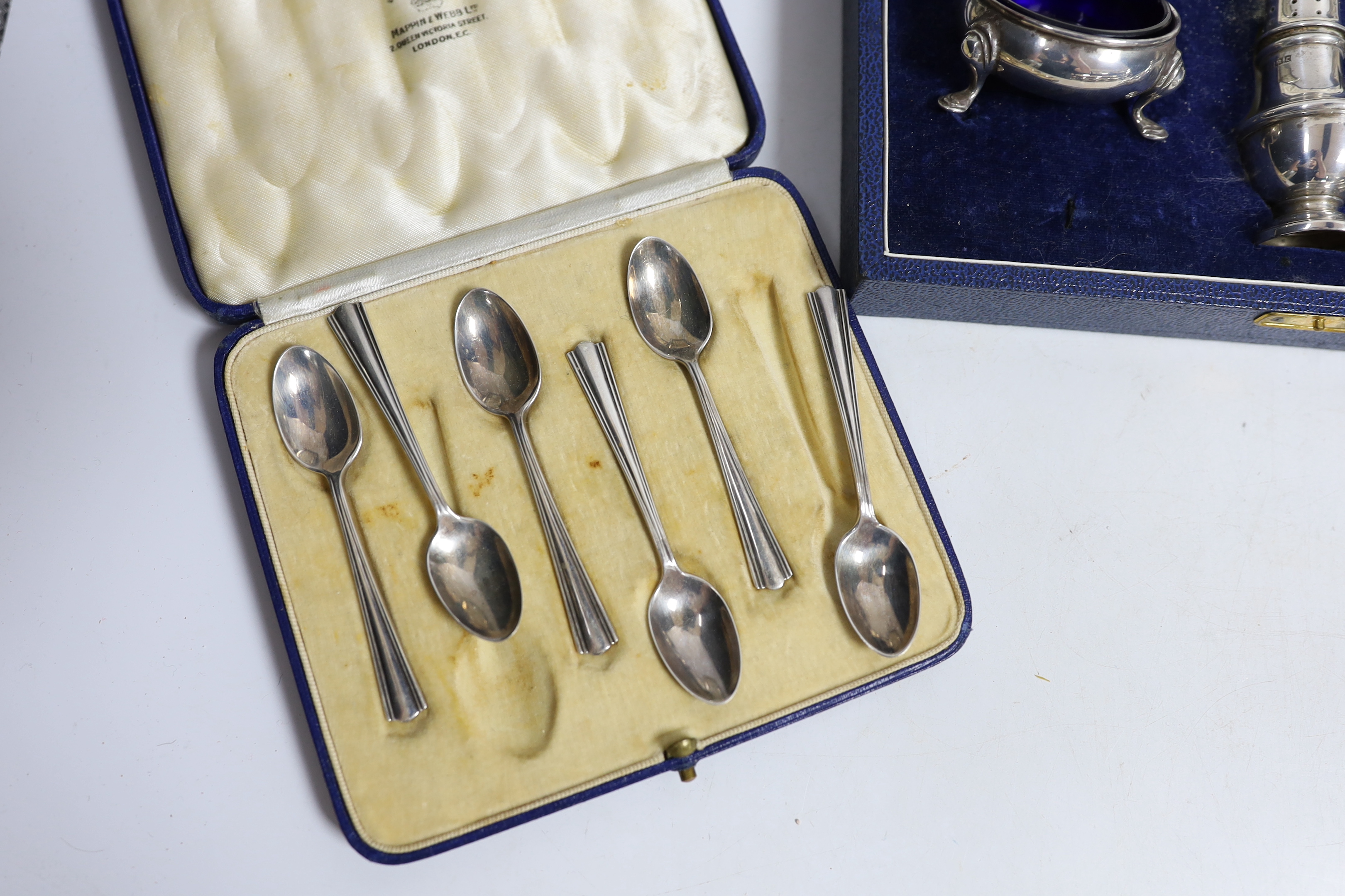 An Elizabeth II cased silver three piece condiment set by Mappin & Webb, a cased pair of Irish silver pepperettes, a cased set of six silver coffee spoons, two silver dishes and a silver mounted photograph frame.